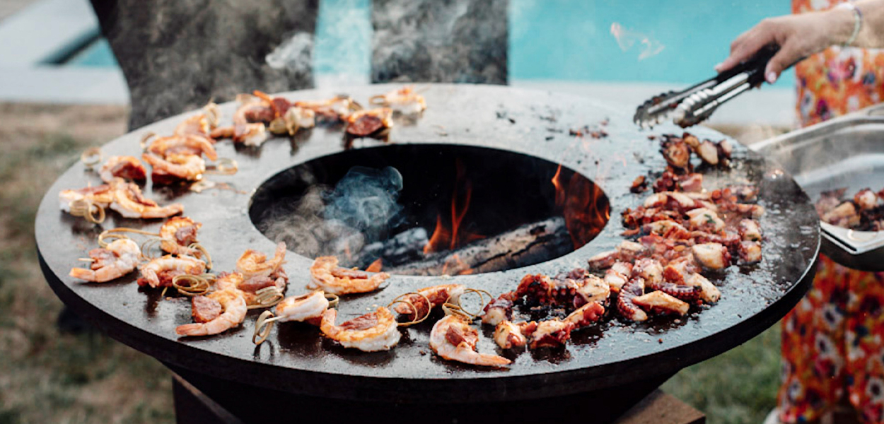 Barbecue grill at a Campo Marbella wedding catering service, fire and smoke at golden hour