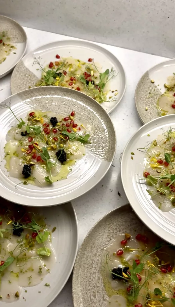 Overhead view of carpaccio starter plates garnished with pomegranate and herbs, ready to serve at a wedding in Marbella